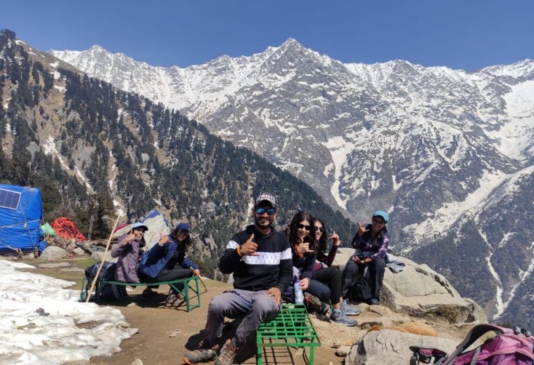 Triund Day Hike from McLeod Ganj 3 Trekkers resting below the snow-covered Dhauladhar mountains