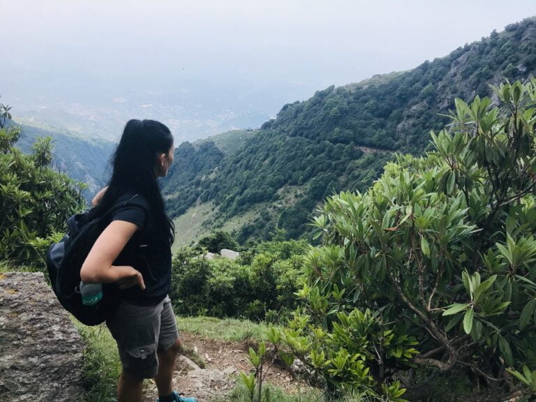 a woman standing on a trail in a forest