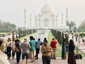 a group of people standing in front of a large building with Taj Mahal in the background