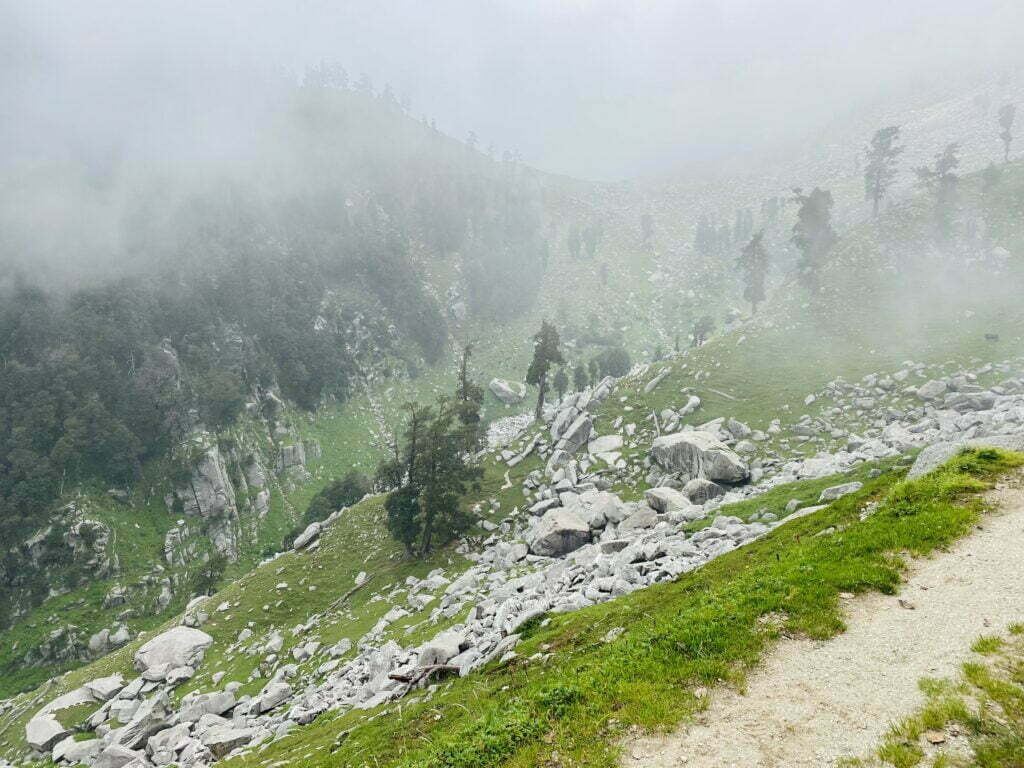 Misty mountain trail with rocky slopes on the Seven Lakes Trek in the Dhauladhar Range near Dharamshala