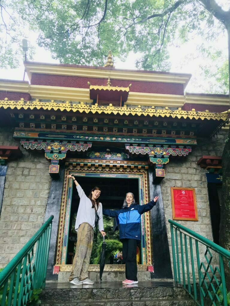 International travelers posing at the entrance of a Tibetan Buddhist monastery near Dharamshala, Himachal Pradesh