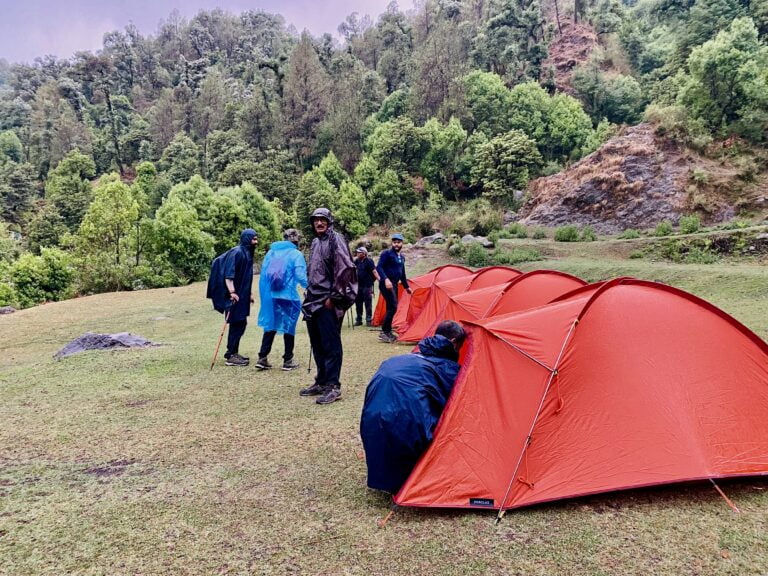 Trekkers setting up tents at a Himalayan campsite near Dharamshala in Himachal Pradesh
