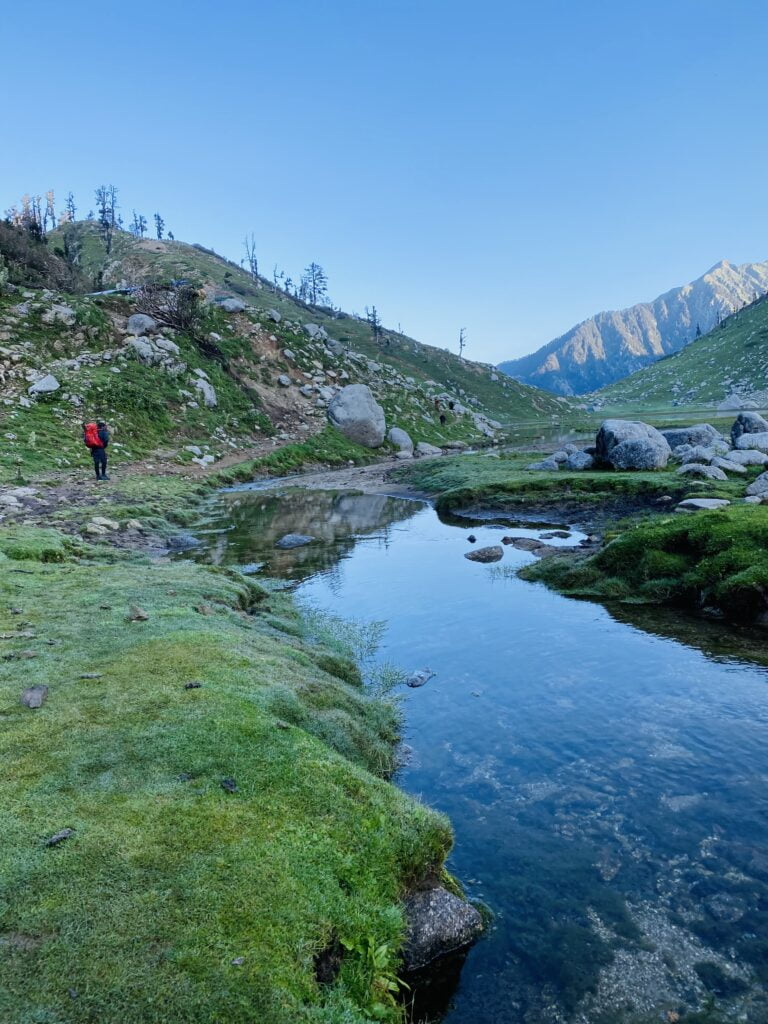 Trekker walking beside an alpine stream on a mountain trail near Dharamshala