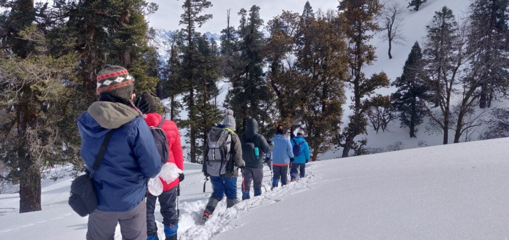 Group of trekkers walking through snow on the Kedarkantha trek in Uttarakhand