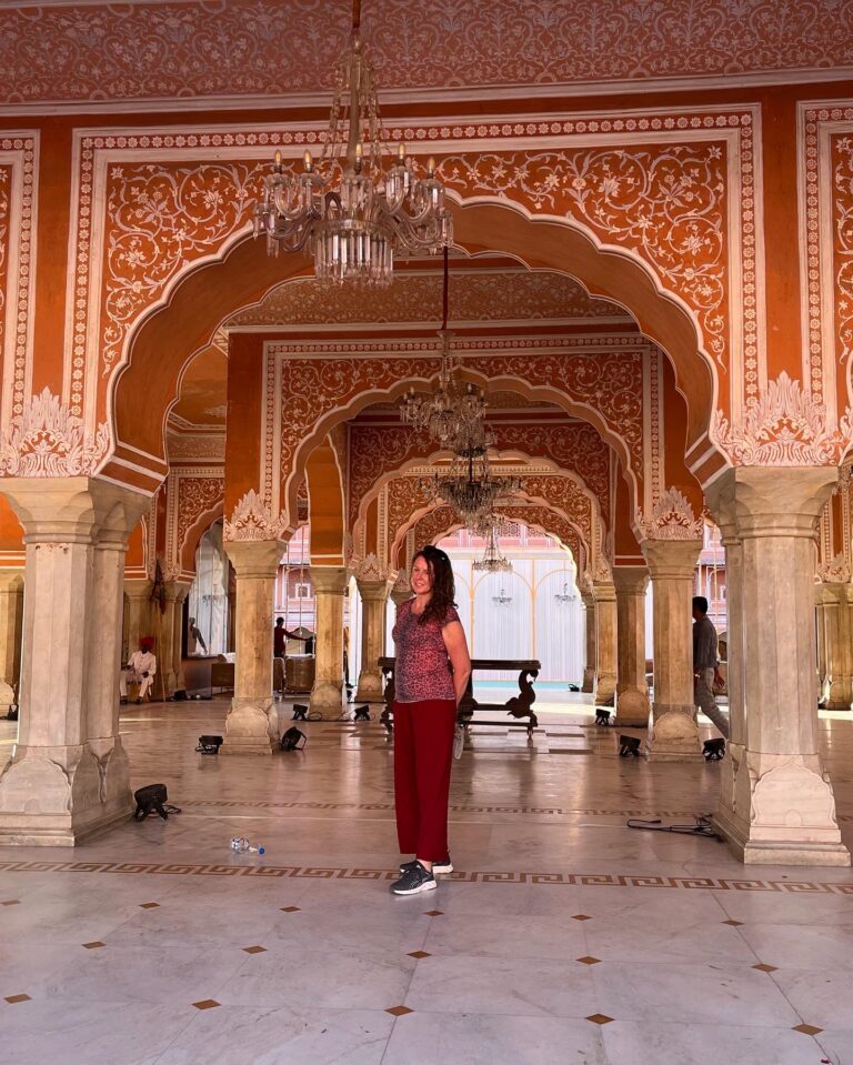 Visitor beneath painted arches and chandeliers in a palace hall in Jaipur, Rajasthan