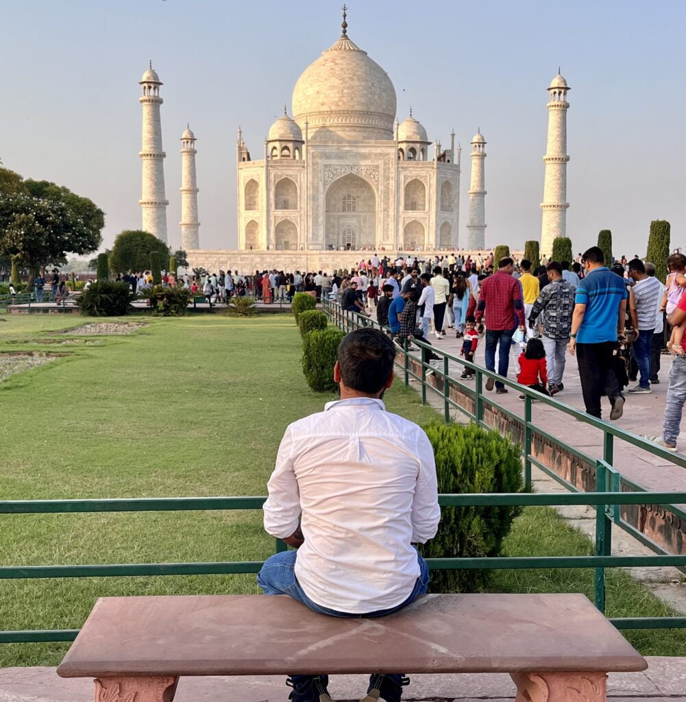 Visitors walking towards the Taj Mahal in Agra with the white marble monument in the background