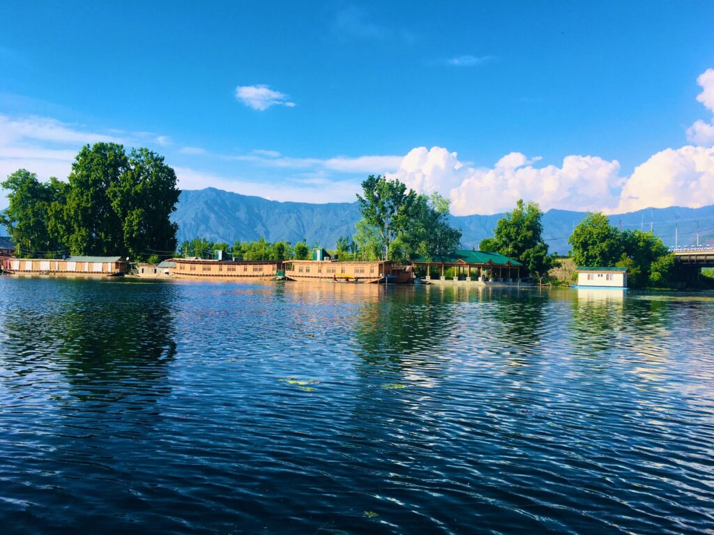 Nigeen Lake in Srinagar with traditional houseboats, calm blue water, and mountains in the background