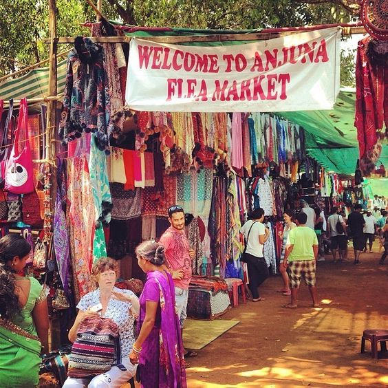 Colorful stalls and visitors at Anjuna Flea Market in Goa selling clothes, jewelry, and handicrafts