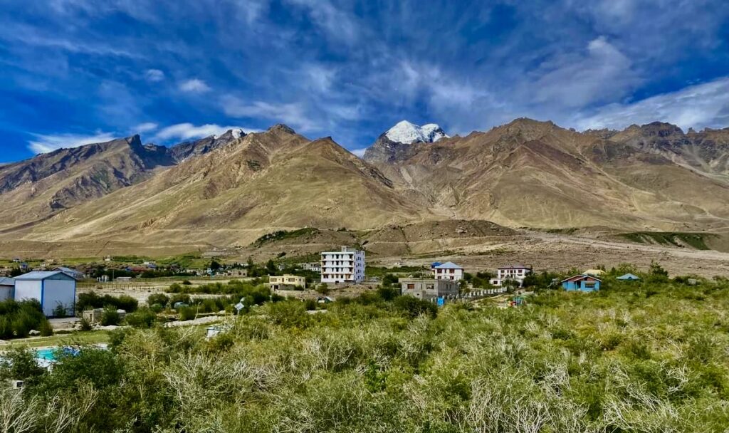 Traditional Ladakhi village landscape on the Markha Valley Trek near Leh, Ladakh, with mountains and green fields.