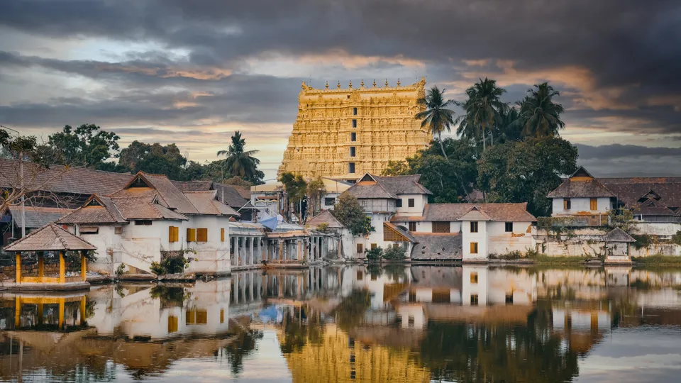 a body of water with buildings and trees with Padmanabhaswamy Temple in the background