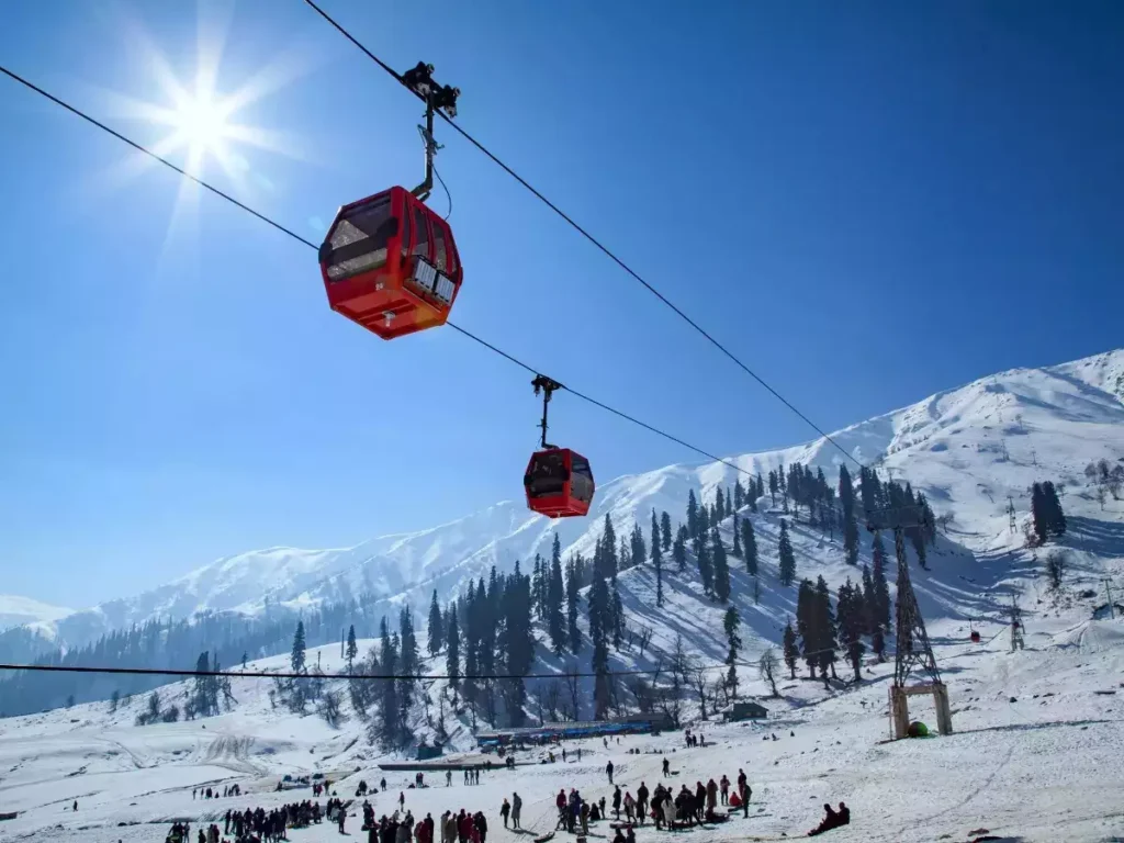 Gulmarg Gondola cable car in winter with snow-covered slopes, pine trees, and skiers in Gulmarg, Kashmir