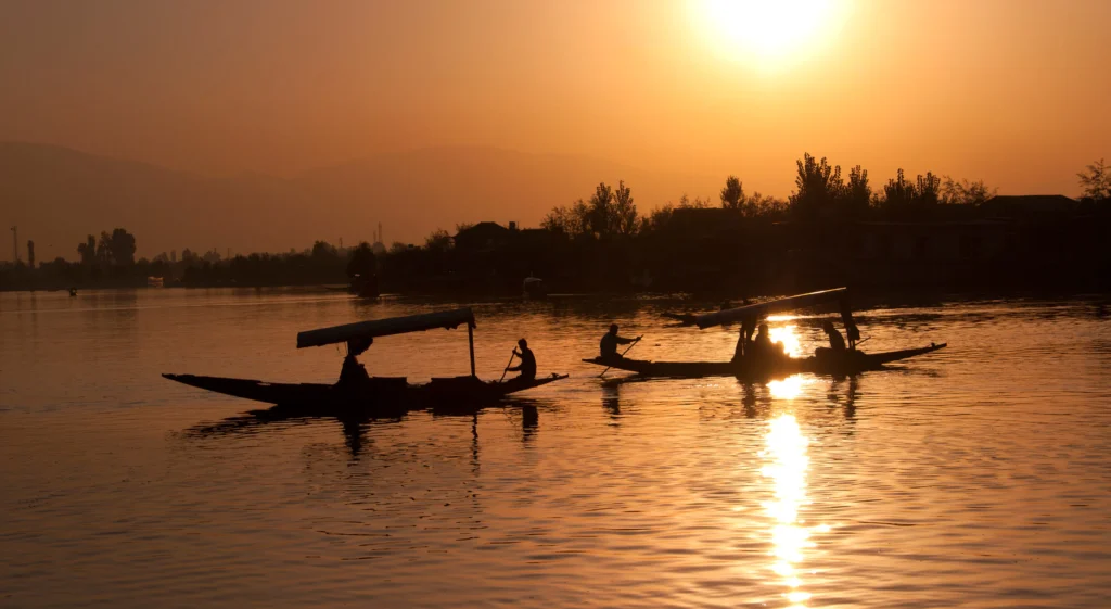 Sunrise over Dal Lake with traditional boats on calm water in Srinagar Kashmir