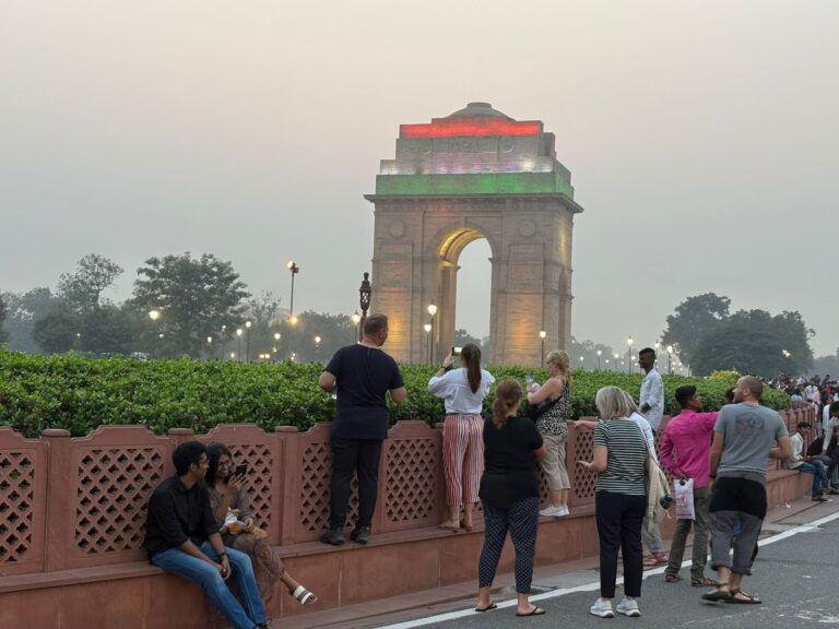 Tourists visiting India Gate in New Delhi during evening with illuminated monument