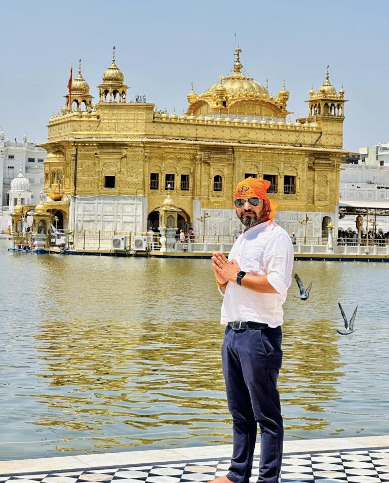 Golden Temple in Amritsar with a visitor offering prayers beside the holy sarovar