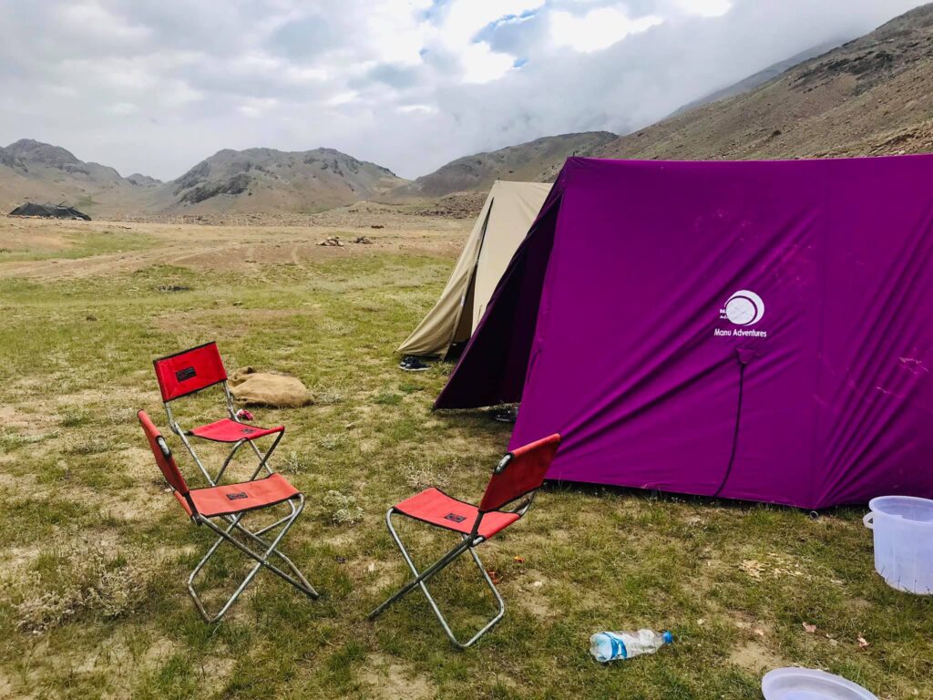 Beyond the Usual: 7 Hidden Adventure Gems in North India You’ve Probably Never Heard Of 3 Camping setup in Spiti Valley with purple tent and chairs in a high-altitude cold desert landscape