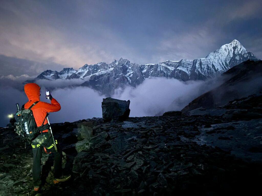 Hidden Himalayan Trails for Sustainable Trekking in 2025 2 Trekker standing on a rocky ridge during the Hanuman Tibba Expedition with snow-covered Himalayan peaks in Himachal Pradesh