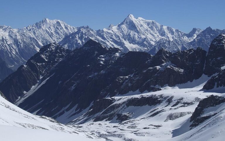 Snow-covered peaks and rugged ridges of Thamsar Pass in Himachal Pradesh with panoramic views of the Dhauladhar and Pir Panjal ranges.