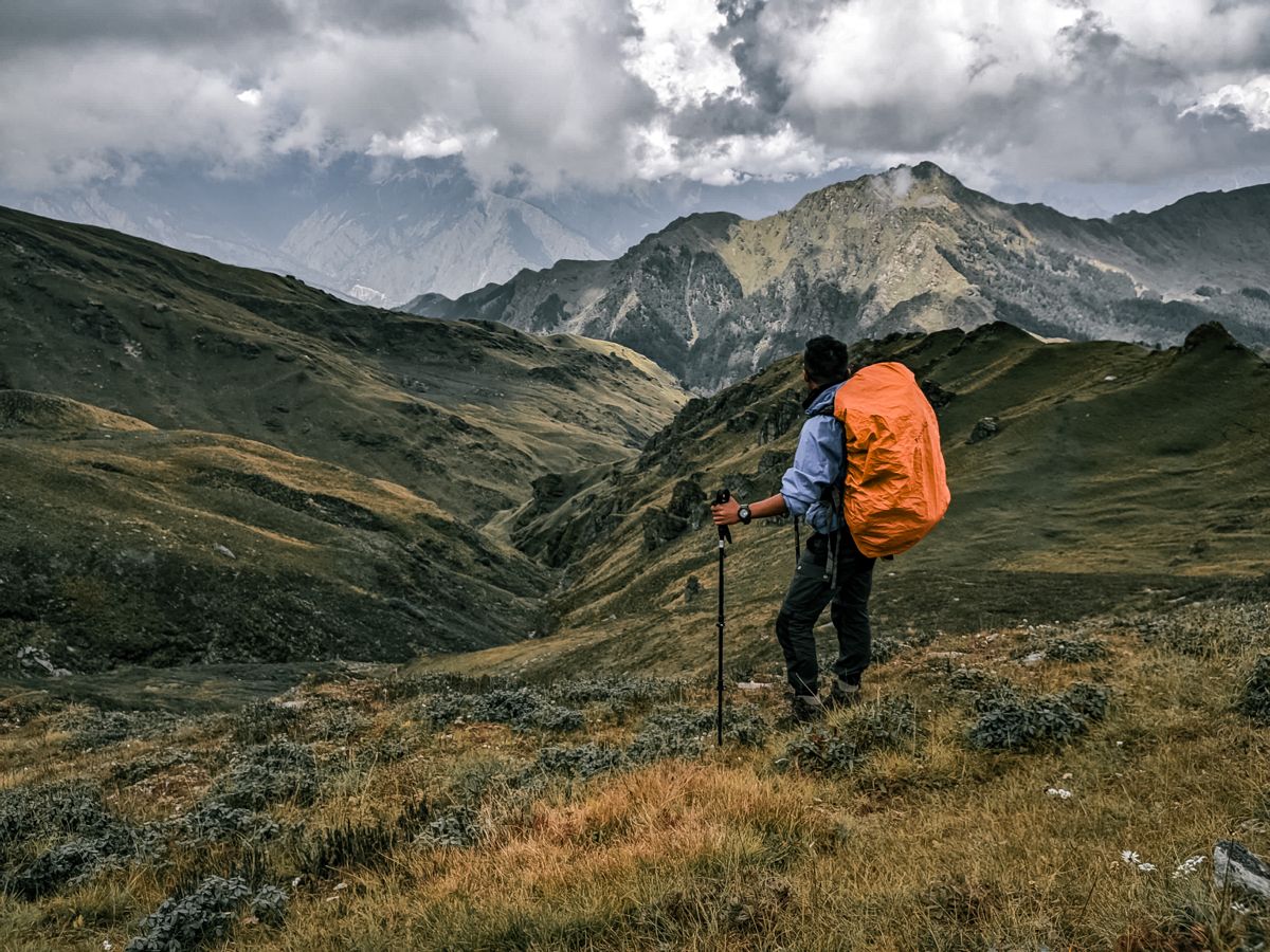 Trekker standing on a high-altitude meadow during the Kundli Pass Trek in the Dhauladhar range near Dharamshala, Himachal Pradesh.