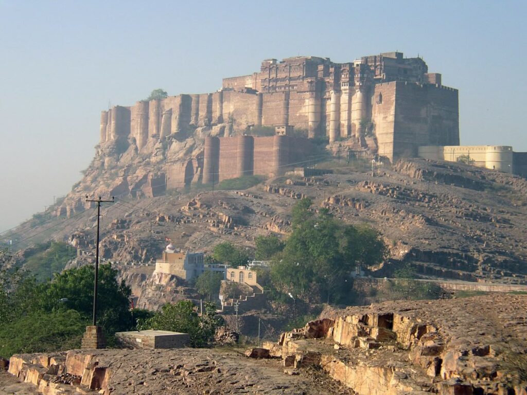 Majestic view of Mehrangarh Fort in Jodhpur, Rajasthan, built on a rocky hilltop with massive sandstone walls and a clear blue sky in the background.