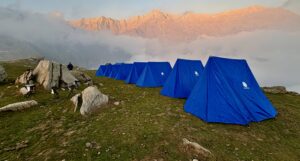 Mountain camping tents set up at a high-altitude campsite with Himalayan peaks during sunrise