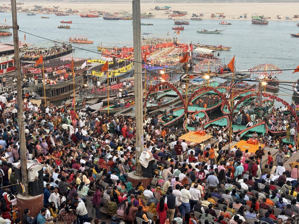 Crowds gathered beside colourful boats along the Ganga riverfront in Varanasi