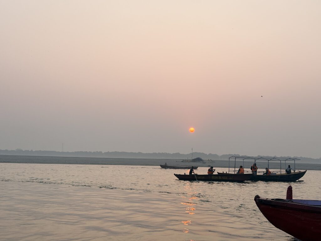 Passenger boats on the Ganga River in Varanasi with a low sun above the water