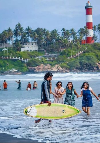 a group of people walking in the water with a surfboard