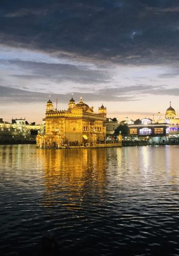 a body of water with Harmandir Sahib lit up at night